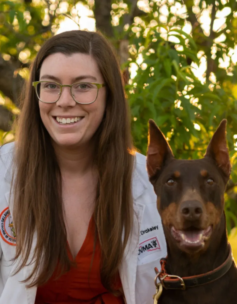 Dr. Molly Drakeley smiling next to a Doberman
